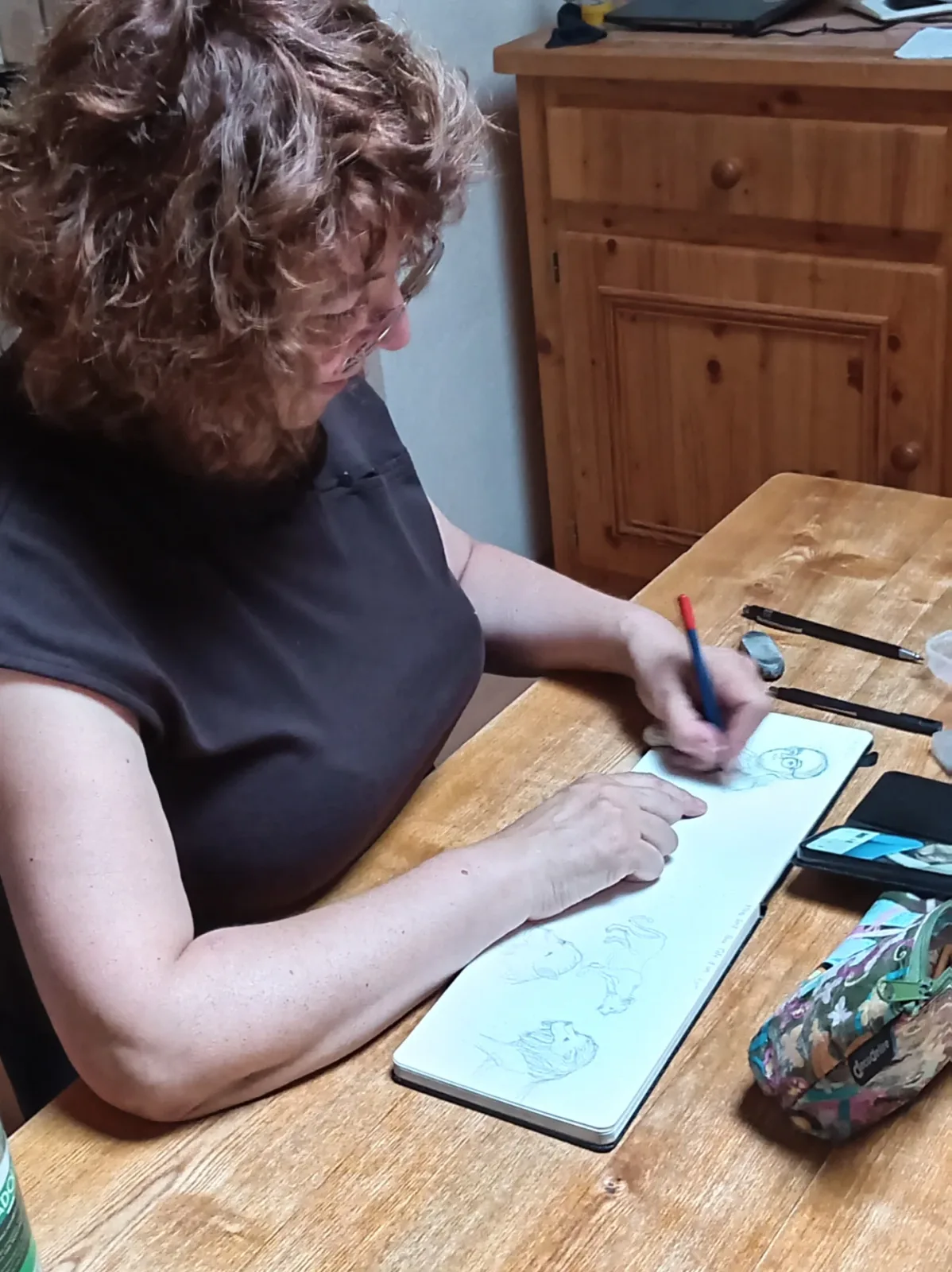 Isabelle Mellah dessinant dans son carnet à sa table de travail.